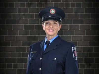Jackie Mussel the newly promoted Norfolk County Fire captain standing against a brick wall wearing her new captain work attire.